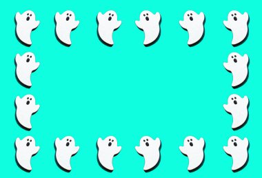 Yeşil arkaplan ve kopyalama alanına izole edilmiş beyaz hayaletler. Cadılar Bayramı süsleri renklidir. Düz konum.