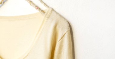 Beyaz elbiseli bir hırka beyaz arka planda asılı duruyor. Yaklaş..