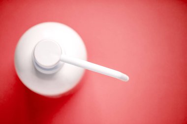 Kırmızı arka planda izole edilmiş antiseptik solüsyonlu şişe ve kopyalama alanı.