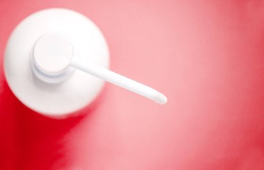 Kırmızı arka planda izole edilmiş antiseptik solüsyonlu şişe ve kopyalama alanı.