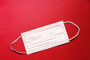 Tıbbi maske, kırmızı arka planda tıbbi koruyucu maske. Tek kullanımlık yüz maskesi ağız ve burnu kapatır. Sağlık ve Tıp Konsepti.