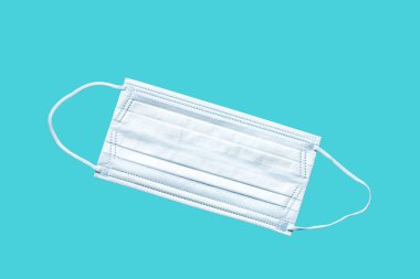Tıbbi maske, mavi arka planda tıbbi koruyucu maske. Tek kullanımlık yüz maskesi ağız ve burnu kapatır. Sağlık ve Tıp Konsepti.