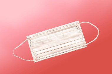 Tıbbi maske, kırmızı arka planda tıbbi koruyucu maske. Tek kullanımlık yüz maskesi ağız ve burnu kapatır. Sağlık ve Tıp Konsepti.