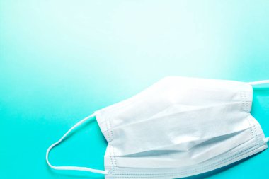 Mavi arka planda beyaz hava koruma maskesi. Tek kullanımlık yüz maskesi ağız ve burnu kapatır. Sağlık ve Tıp Konsepti.