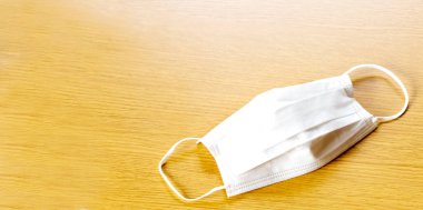 Mavi arka planda beyaz hava koruma maskesi. Tek kullanımlık yüz maskesi ağız ve burnu kapatır. Sağlık ve Tıp Konsepti.