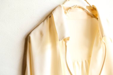 Beyaz gömlekli bir bluz ya da gömlek beyaz arka planda asılı duruyor. Kapatın ve boşluğu kopyalayın..