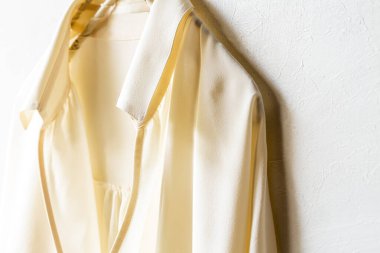 Beyaz gömlekli bir bluz ya da gömlek beyaz arka planda asılı duruyor. Kapatın ve boşluğu kopyalayın..