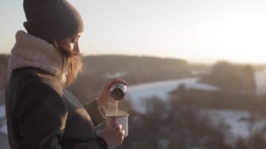 Genç kadın bir termos kış orman içinde gelen çay içmek