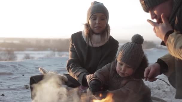 Padre, madre un hijo pequeño asando los malvaviscos en el bosque de invierno — Vídeo de stock