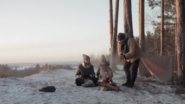 Père, mère un petit fils rôtissant les guimauves dans la forêt d'hiver — Video