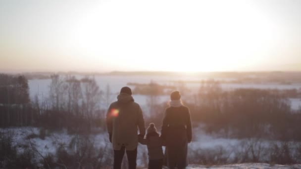 De familie staat in de winter bos tijdens zonsondergang — Stockvideo