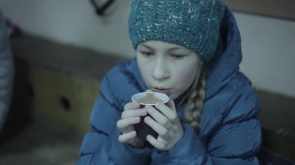 Schattig jong meisje in blauwe vacht drinken warme chocolademelk na schaatsen — Stockvideo