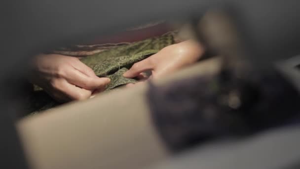 Woman sews a green blouse. shooting through a sewing machine — Stock Video