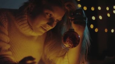genç kız bir kırmızı Noel topları, Noel ışıkları görünüyor.