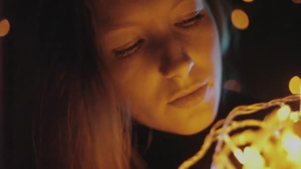 Belle jeune fille regarde une guirlande jaune, lumières de Noël . — Video