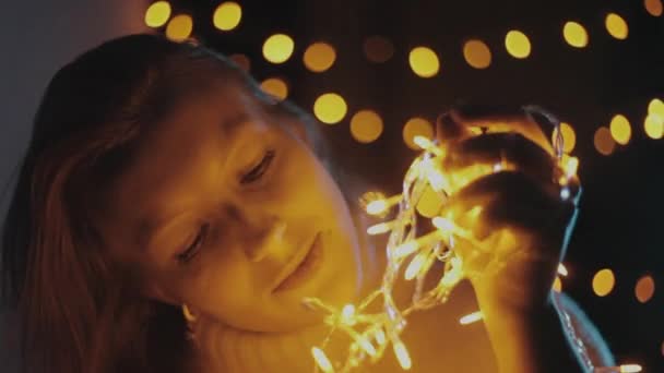 Красивая молодая девушка держит желтую гирлянду, рождественские огни . — стоковое видео