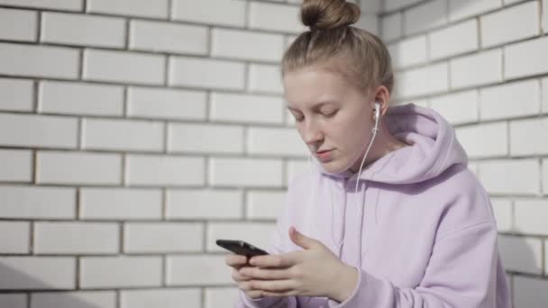 Aantrekkelijke jonge vrouw luisteren muziek op smartphone in huis — Stockvideo