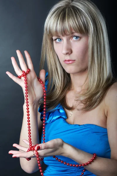 Femme en robe bleue avec des perles à la main — Photo