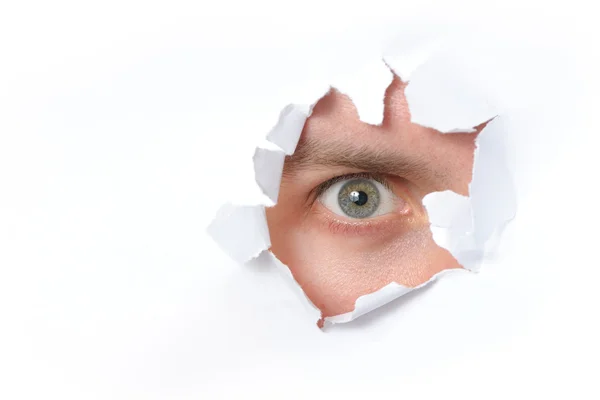 Ögat ser genom ett hål i papper — Stockfoto