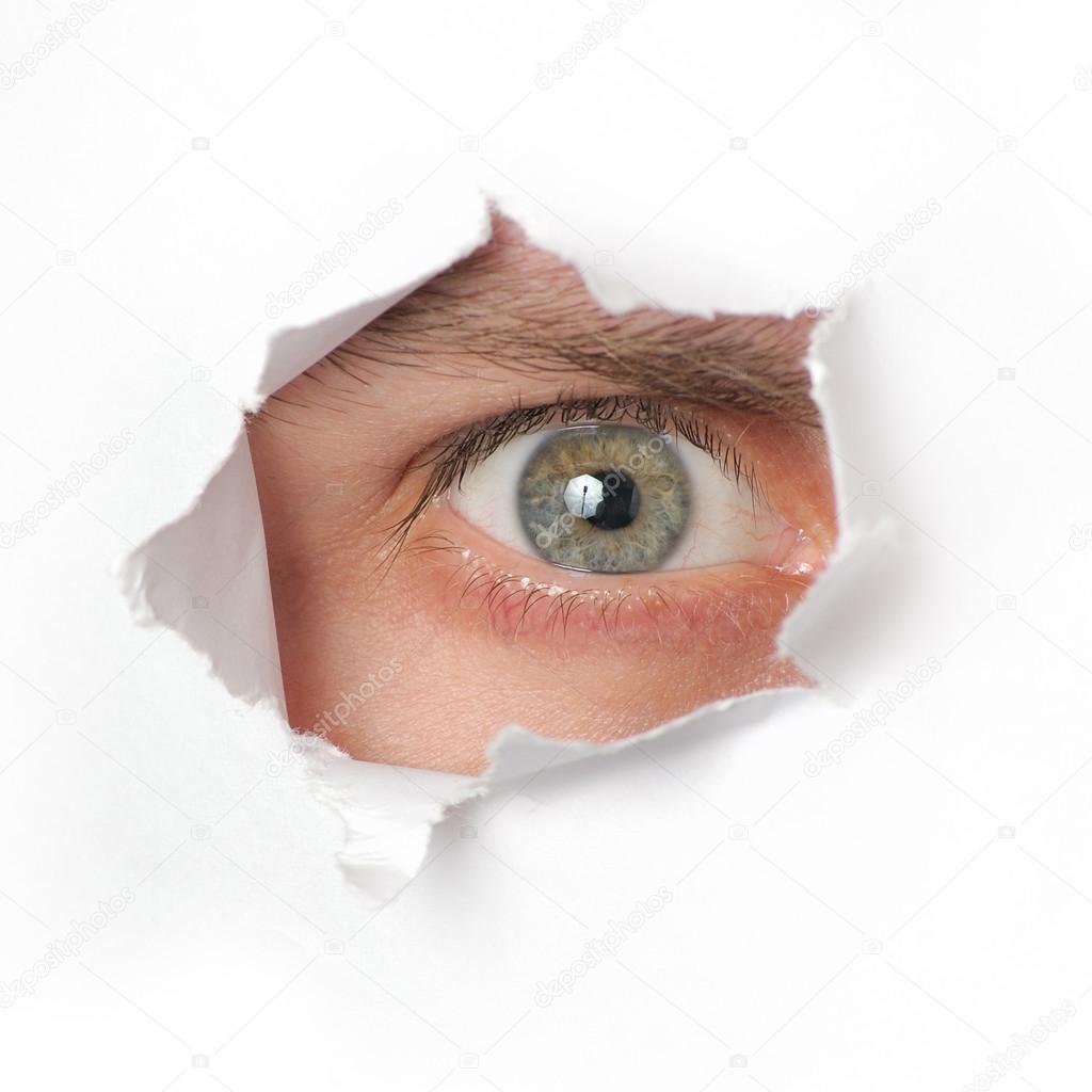 Eye looking through a hole in paper