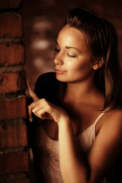 Beautiful woman near brick wall — Stock Photo, Image