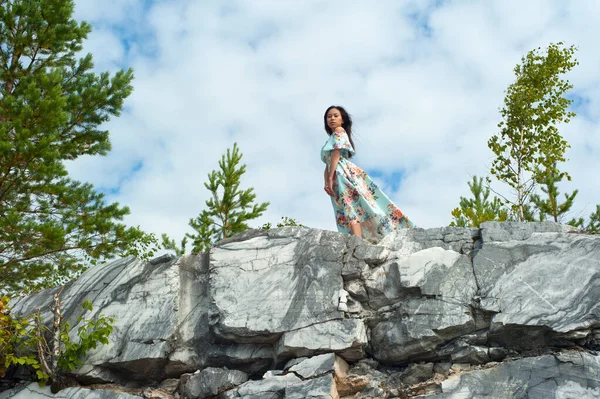 Junge Frau in langem Kleid posiert auf Marmorfelsen — Stockfoto