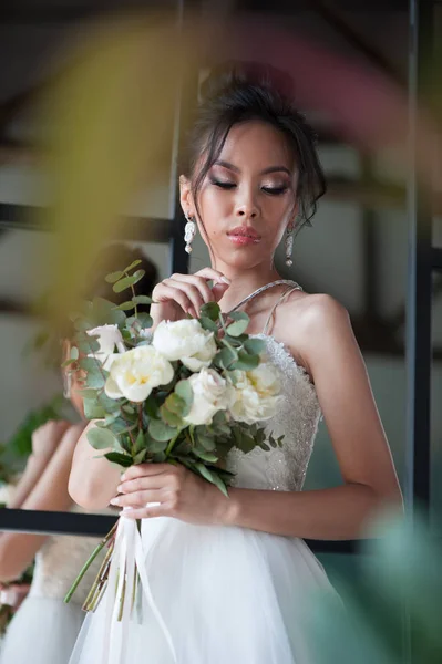 Aziatische bruid met bloemen in witte jurk — Stockfoto