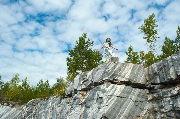 Молодая женщина в длинном платье позирует на мраморной скале — стоковое фото