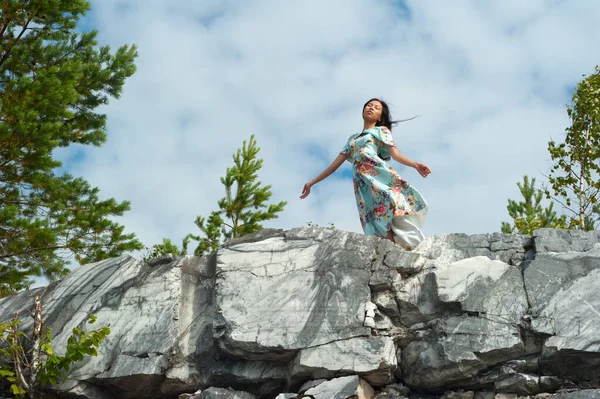 Jovem em vestido longo posando em pedra de mármore — Fotografia de Stock