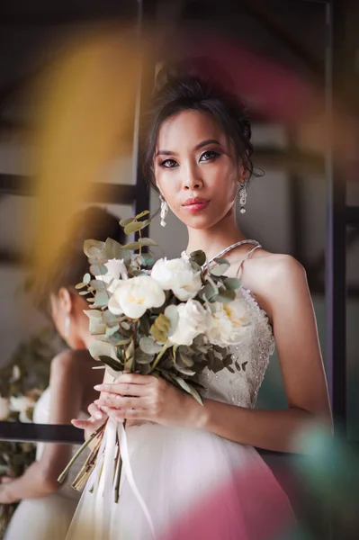 Азиатская невеста с цветами в белом платье — стоковое фото