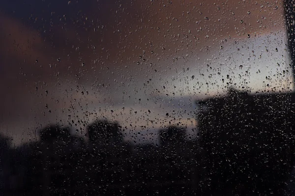 在暮色的城市的背景下 窗上的雨滴 — 图库照片