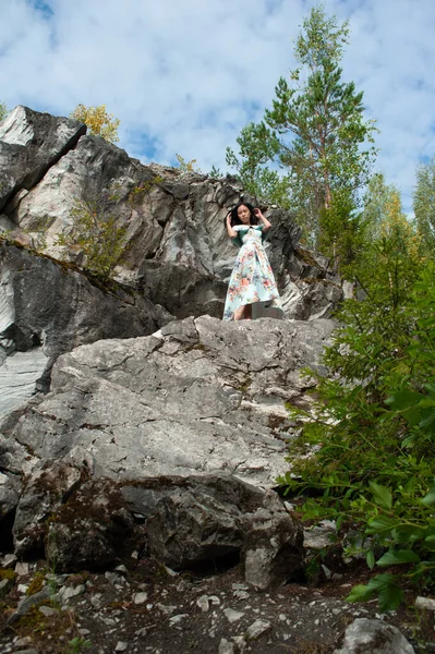 在公园里穿着漂亮衣服的年轻女子在石头上 — 图库照片