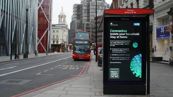 Londres, Reino Unido, 20 de marzo de 2020: Estación de autobuses vacía cerca del área de Victoria en el bloqueo del coronavirus de Londres. Messege sobre panel led sobre distanciamiento social y COVID-19 —  Fotos de Stock