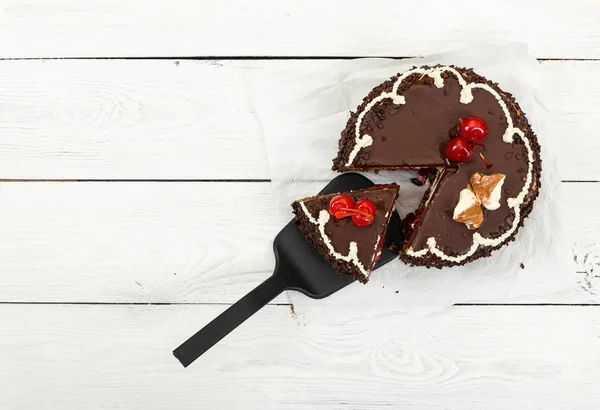 Pastel de chocolate con cereza sobre fondo de madera . — Foto de Stock