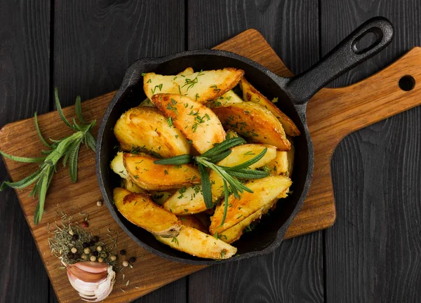 Roasted potato with fresh rosemary in cast-iron pan. Top view. — Stock Photo, Image