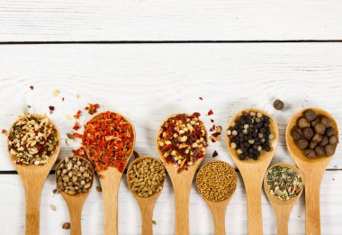 Tahta kaşık ahşap arka plan üzerinde içinde farklı baharatlar. 