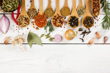 Tahta kaşık ışık arka plan üzerinde içinde çeşitli baharatlar.  