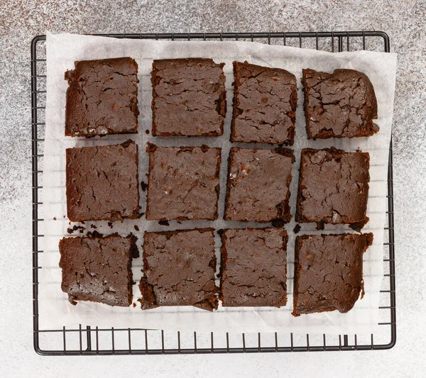 Chocolate brownie cakes on baking rack on grey stone background. Top view.
