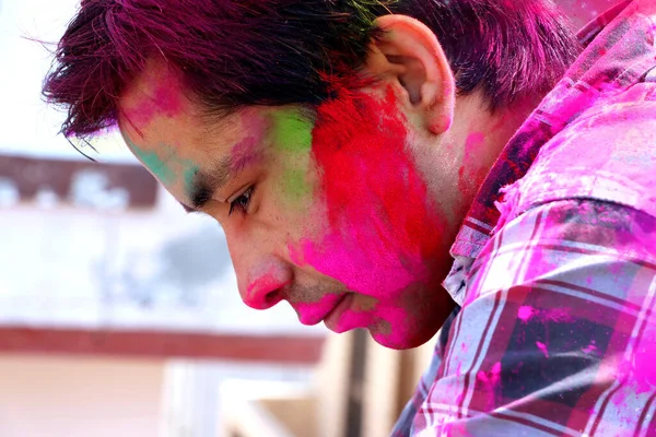 Closeup shot of Indian young man covered with multi color dry paint at Holi Festival.