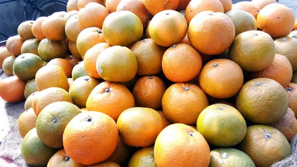 Fresh orange fruit pile on stall in supermarket