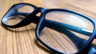 Ahşap arka planda siyah çerçeveli gözlükler, masa. Yukarıdan görüntüle.