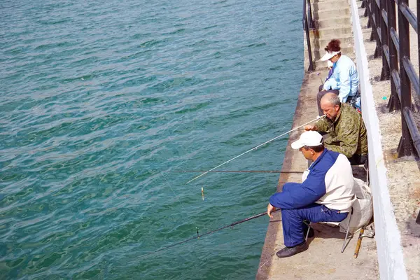 Pêcheurs avec cannes à pêche sur la jetée, engagés dans la pêche . — Photo