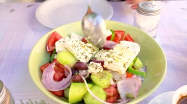 Sebze ve peynirli Yunan salatası. Kadın kaşıkla tabakta salata karıştırıyor..
