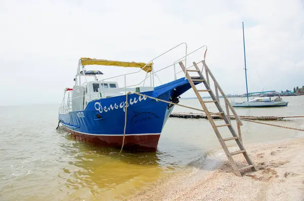 Bateau bleu, petit, vieux pour des excursions touristiques en mer. Amarré à la rive, la rampe vers le bas . — Photo