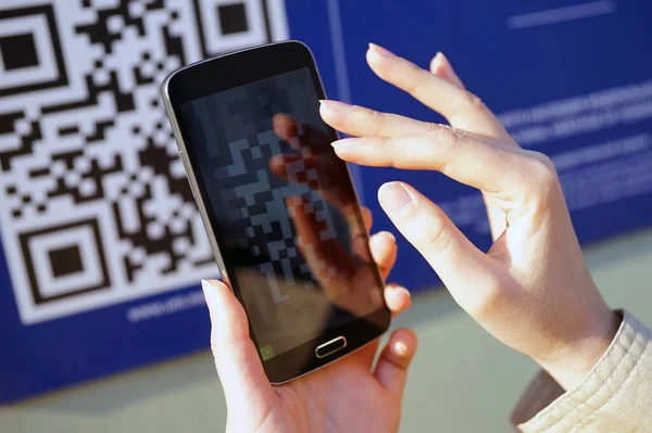 Moskova - Ocak 2020: QR kodu, akıllı telefonla tarama. Duvardaki şifrenin görüntüsü, kızın elindeki telefon, kodun görüntüsünü hedefliyor. Taranan kod t üzerinde gösterilir