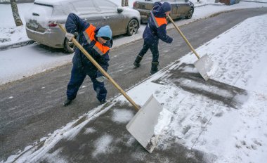 Workers in uniform with big shovels. Snow removal on the city streets.