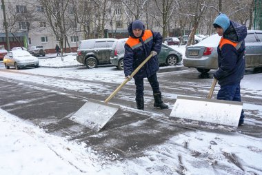 Workers in uniform with big shovels. Snow removal on the city streets.