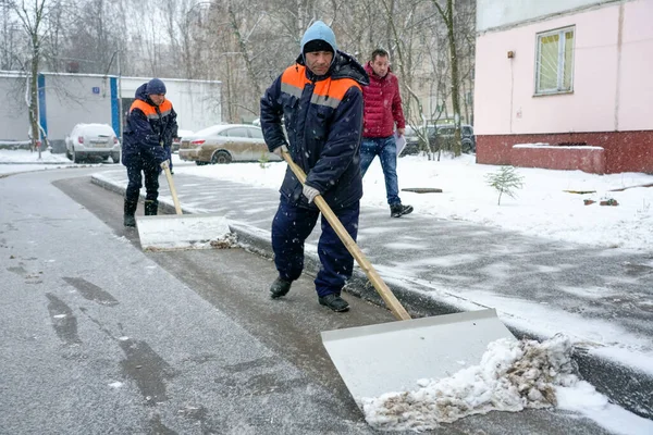Werknemers in uniform met grote schoppen. Sneeuw verwijderen op de straten van de stad. — Stockfoto