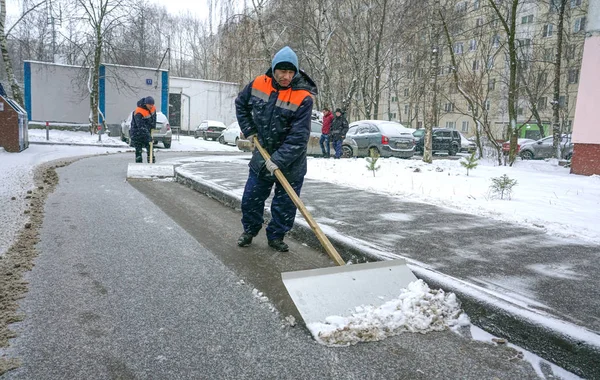 Werknemers in uniform met grote schoppen. Sneeuw verwijderen op de straten van de stad. — Stockfoto