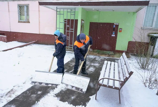Trabajadores en uniforme con grandes palas. Eliminación de nieve en las calles de la ciudad . — Foto de Stock